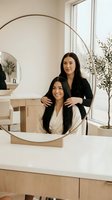 Professional hairstylist working with client in modern salon interior with natural lighting and minimalist design for beauty services.