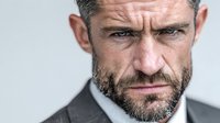 Intense mature businessman with beard and wrinkles showing determination and focus in professional corporate headshot for business leadership concepts.