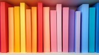 Colorful book spines arranged in rainbow spectrum order from red to blue on bookshelf, creating gradient pattern for education and library concepts.