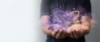 Hands holding glowing atom model with purple and gold light trails, representing science, technology, innovation, and atomic energy research for educational and corporate use.