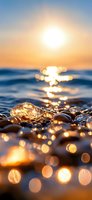 Sunlight reflecting on wet pebbles and ocean waves creates magical bokeh effect during golden hour sunset, with sparkling water drops and glistening stones.