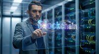 Professional businessman touching holographic blockchain text in modern data center server room with digital particles and network connections.