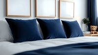 Elegant bedroom interior with navy blue pillows and white bedding, empty wooden frames on wall, minimalist modern decor with soft natural lighting.