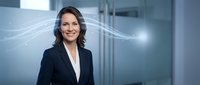 Professional businesswoman with flowing digital network connections in modern office environment representing technology and corporate success.