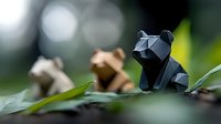 Low poly paper bear figure in dark blue sits on green leaf with blurred natural background, artistic origami sculpture creates minimalist geometric animal shape.
