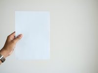 Male hand holding blank white paper sheet against neutral background. Suitable for mockups, presentations, advertising campaigns, and business communications.