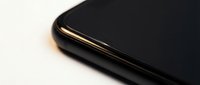 Black smartphone with gold metallic frame detail showing premium design and craftsmanship for technology and mobile device concepts.