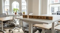 Wooden letter blocks spelling prepared on modern office desk with chairs and windows overlooking urban street, suitable for business and workplace concepts.