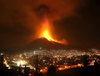 Dramatic volcanic eruption at night illuminating city below with glowing lava and ash cloud, urban landscape with mountain volcano in background showing nature's raw power.