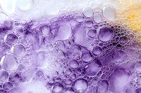 Abstract purple and yellow bubble foam texture with translucent spheres creating organic patterns for modern design backgrounds and creative projects.