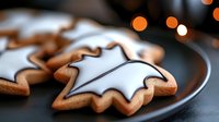 Homemade star-shaped gingerbread cookies with white icing glaze on dark plate against blurred bokeh lights background, festive Christmas baking.