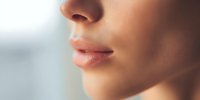 Close-up of woman's lips and nose in soft natural light showcasing smooth skin texture and natural beauty for skincare and cosmetic concepts.