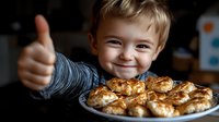 Young caucasian boy showing thumbs up with excited smile while presenting homemade baked pastries on white plate, dark background with natural lighting.