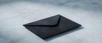 Black envelope on white surface with dramatic lighting and shadows creating elegant minimalist composition for business correspondence and mailing concepts.