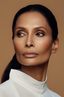 Elegant African American woman with flawless makeup and defined cheekbones wearing white turtleneck against brown background, fashion beauty portrait.