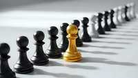 Golden chess pawn stands out among black pawns in strategic leadership concept for business success and competitive advantage.