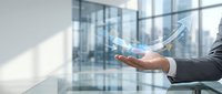 Business professional holding holographic growth arrow in modern office environment showcasing digital transformation and financial success concepts.