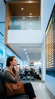 Professional businesswoman waiting at modern airport terminal with departure board, business travel and corporate mobility concept.