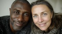 Diverse mature couple smiling together in close-up portrait, showing genuine connection and happiness in their interracial relationship.