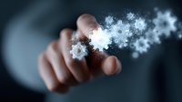 Close-up of businessman's hand touching virtual gear icons with glowing digital particles, representing technology innovation and business automation solutions.