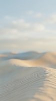 Soft-focused sand dune with rippled texture in warm golden light, distant mountains and cloudy sky creating serene desert landscape suitable for travel, nature, and wellness backgrounds.