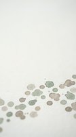Abstract watercolor spots in earthy green and brown tones scattered on textured paper background for creative design projects.