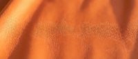 Closeup of soft orange fabric texture with natural folds and shadows, suitable for textile, fashion, and design backgrounds.
