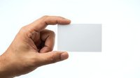 Hand holding blank white business card isolated on white background, ready for custom branding and design mockup purposes.