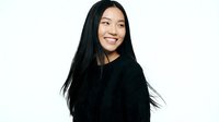 Happy young Asian woman with long black hair smiling warmly in black sweater on white background isolated for design use in marketing materials.