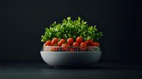 Fresh cherry tomatoes and green arugula leaves in modern white ceramic bowl against dark background, dramatic lighting creates gourmet food composition.