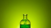 Fresh green liquid in glass bottle against vibrant lime background, suitable for beverage, health drink, and product marketing campaigns.