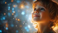 Caucasian child with blonde hair gazing upward at magical glowing lights and bokeh effects against dark blue background, expressing wonder and imagination.