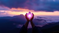 Silhouetted hands holding glowing light against purple mountain sunset sky, symbolizing hope, spirituality, and inner power in nature landscape background.