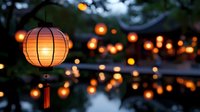 Glowing orange paper lanterns illuminated at dusk create magical atmosphere with blurred bokeh reflections on water surface, festive outdoor party lighting.