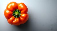Fresh ripe red bell pepper with green stem photographed from above on gray background, isolated with dramatic lighting and copy space for food design.