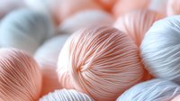 Soft pastel colored yarn balls in peach and white tones creating gentle textured pattern with delicate striped details, suitable for craft and knitting backgrounds.