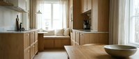 Warm wooden kitchen with natural light from large windows, light wood cabinetry, and minimalist decor. Suitable for interior design, home improvement, and lifestyle publications.