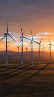Wind turbines at sunset with digital circuit overlay representing smart grid technology and renewable energy innovation in sustainable power generation.