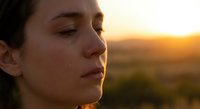 Young woman with closed eyes enjoying peaceful sunset moment in natural outdoor setting with warm golden light creating serene atmosphere for meditation and relaxation.