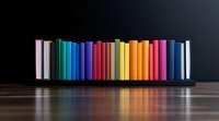 Colorful books arranged in rainbow spectrum order on wooden shelf against dark background, creating reflection on glossy surface. Educational concept.