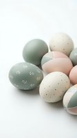 Pastel Easter eggs with delicate patterns in soft green, pink and cream colors arranged on white background for spring holiday celebrations.