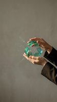 Hands holding glowing green recycling symbol with sparkling particles against neutral background, representing environmental sustainability and eco-friendly business practices.