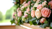 Fresh pink and peach roses with green foliage arranged on wooden surface against blurred natural background, romantic floral composition for wedding or celebration.