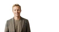 Caucasian male professional with blonde hair wearing casual business attire, smiling at camera against white background for corporate portraits and business communications.