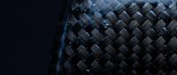 Dark woven carbon fiber texture with diagonal herringbone pattern, ideal for industrial design, technology backgrounds, and modern material concepts.