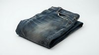 Folded blue denim jeans on white background, casual wear apparel isolated for fashion design and clothing mockups.