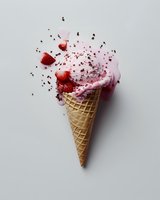 Strawberry ice cream cone with chocolate sprinkles exploding in dynamic composition against light background. Fresh berries and cream create dramatic food motion.
