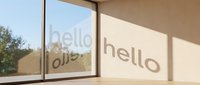 Sunlit modern room with hello text on window casting shadow on wall, minimal interior with natural light and warm tones.