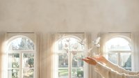 Hands releasing white paper doves through arched windows with soft natural light creating peaceful freedom concept for wellness and spirituality themes.