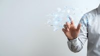 Businessman touching digital interface with floating icons and data visualization elements representing modern technology and business innovation.
